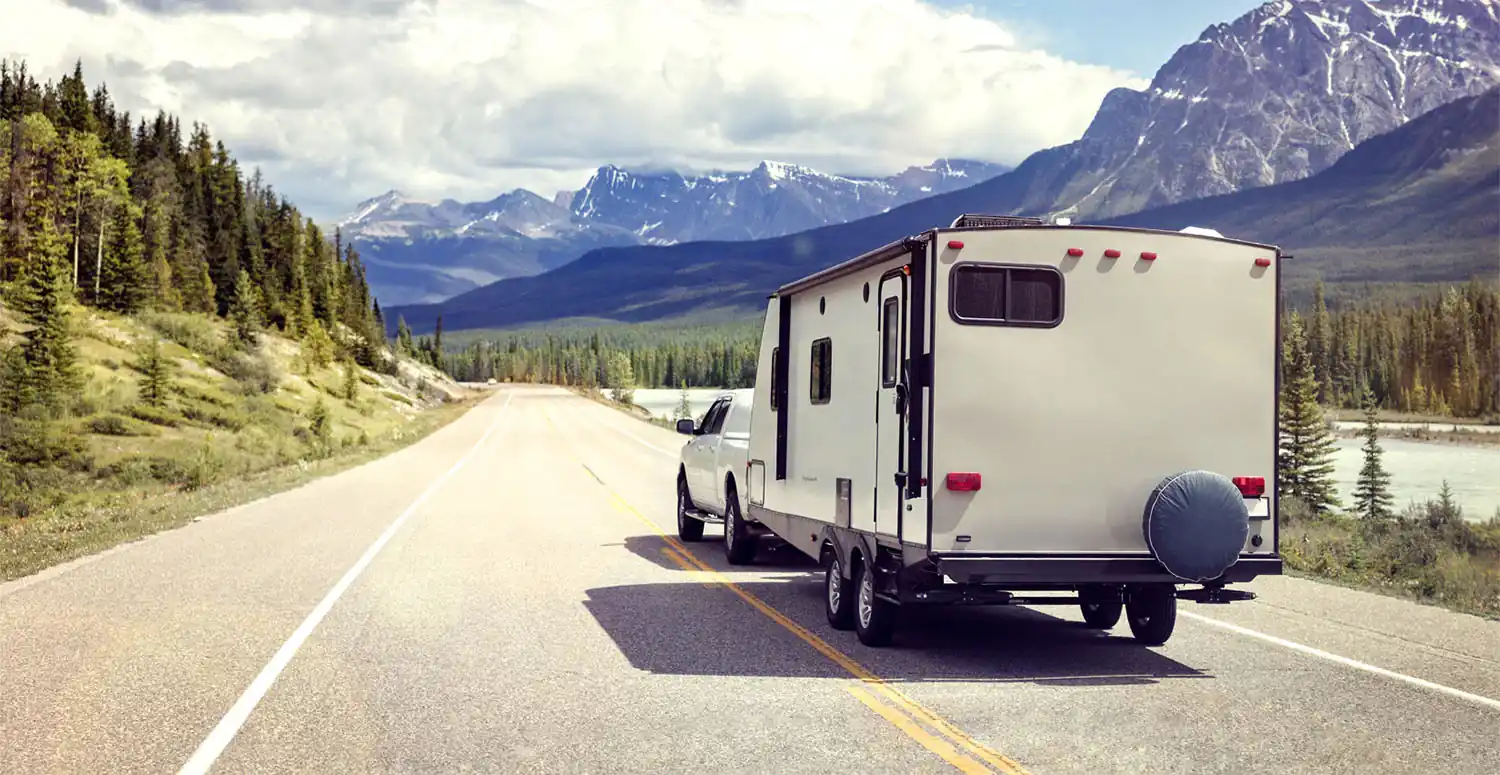 Pickup truck towing a travel trailer on a mountain road